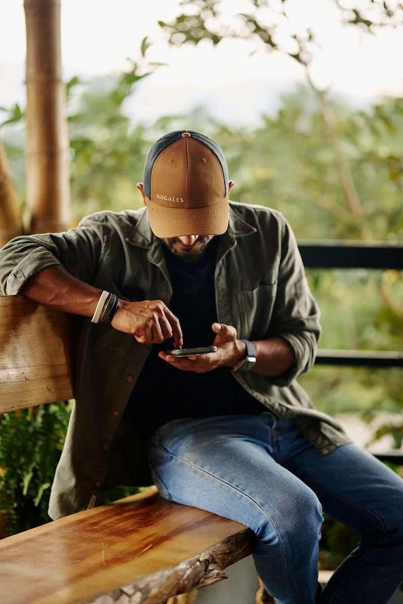 Productor de café de Finca Nogales en Huila, Colombia, revisando datos en su móvil entre cafetales